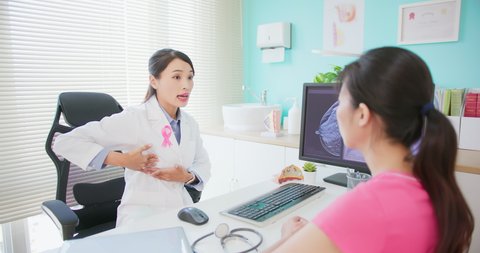 asian woman has breast cancer diagnosis in hospital - female doctor showing mammography test results and xray to patient on computer and giving health education about examination by self