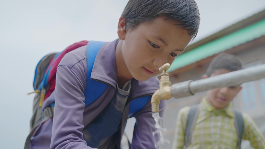close up shot of a young little school boy with backpack drinking clean water from a running tap in a rural village. Concept of a natural resources conservation Royalty-Free Stock Footage #1080199796