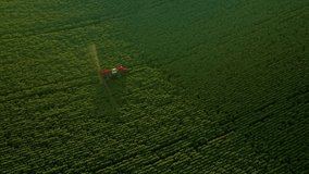 Scenic view from a drone flying over tractor spraying green fields. Organic irrigation field. Location Ukraine agrarian region, Europe. Cinematic aerial shot. Beauty of earth. Filmed 4k, drone video.
