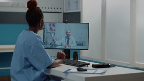 Woman nurse using computer for video call with doctor in cabinet. Medical assistant talking to medic on online remote conference for telehealth and telemedicine. Specialist on call