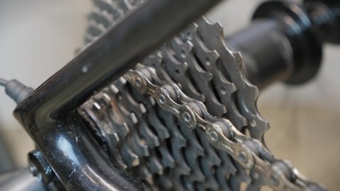 Bicycle wheel gear and chain in motion. Bike drivetrain and cassette, close up. Bike repair. Cycling workshop. Rotating bicycle chain and gears to test bicycle