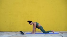 Cheerful young millennial woman trying to replicate asanas laughing at failures during training, positive female having fun browsing on digital tablet online tutorial yoga classes