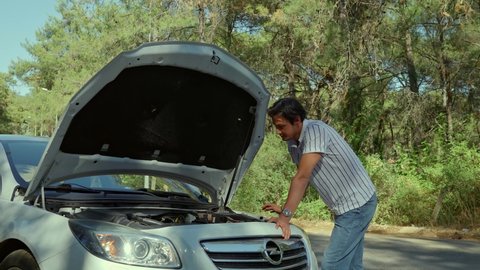 Mugla,Turkey-06.01.2021:Sad man standing by her broken down car. Man worrying about stress, trying to figure out where the fault is in her car with the engine door open.Car crash.Car breakdown.