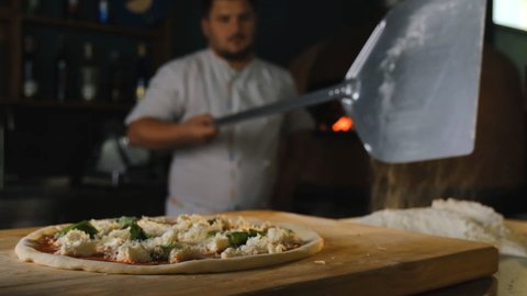 Cooking pizza in an Italian restaurant. Pizzaiolo puts pizza in the hot oven.
