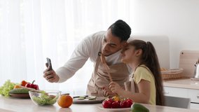 Family Fun. Middle-Eastern Dad And Little Daughter Making Selfie On Phone While Making Salad For Dinner Together In Kitchen At Home. Father Bonding With Kid Taking Photo On Cellphone