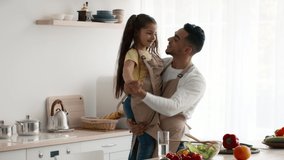 Arab Dad And His Daughter Dancing Bonding Together Having Fun In Modern Kitchen While Preparing Dinner On Weekend. Joy Of Fatherhood Concept. Slow Motion