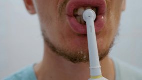 Yellow teeth. Close-up. Man brushing his teeth with an electric brush