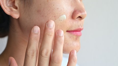 Asian woman applying moisturizer cream for treat and improve her aging skin. Moisturizing everyday can reduce the chance of developing extreme dryness or oiliness.