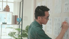 Pre-Production For Film Movie Story Concept : Asian Man Drawing Storyboard Animation Comic Cartoon, Design Creative Scene Layout At Studio. Behind Making Work Before Production Films Or Video Shot
