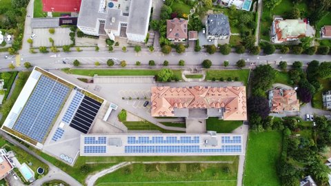 Aerial top down drone footage of the Guintzet area in Fribourg, Switzerland with a school covered by solar panels. 