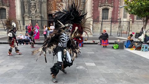 Mexico City, Mexico - October 3, 2021: People wearing ornaments and body paint representing the Aztec Mexica ethnic group performs in front of the Metropolitan cathedral, historic center of CDMX.