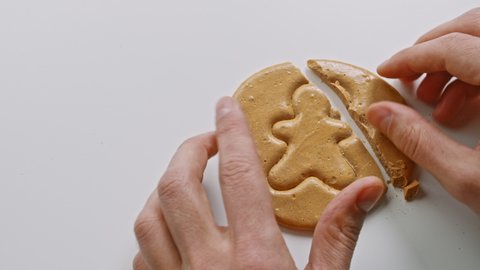 Men's hands break brown sugar caramel candy cookies in the shape of a man. Close-up of survival game