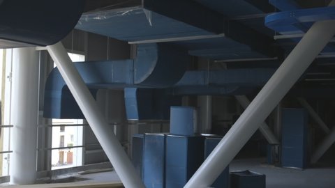 Detail of hanging air conditioner ducts in a big industrial building under construction. Camera panning