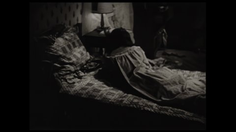 1950s: Girl tosses and turns in bed. Girl kicks off sheets and stands from bed.