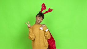 Young woman with christmas hat smiling and showing victory sign with a cheerful face over isolated background. Green screen chroma key