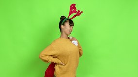 Young woman with christmas hat suffering from pain in shoulder for having made an effort over isolated background. Green screen chroma key