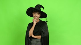 Young woman wearing witch hat standing and looking to the side over isolated background. Green screen chroma key