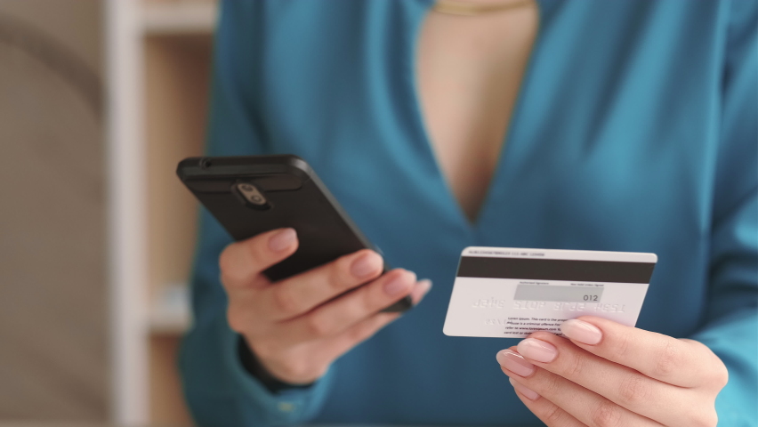 Cashless payment. Banking operation. Checking balance. Money transaction. Closeup of woman hands using ebank app on phone with credit card confirming purchase indoors. Royalty-Free Stock Footage #1080238601