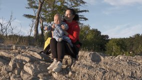 Happy mother playing with her baby on a walk, cute caucasian six month old baby boy smiling outdoors, concept of children, parenthood, childhood, maternity, motherhood. High quality 4k footage