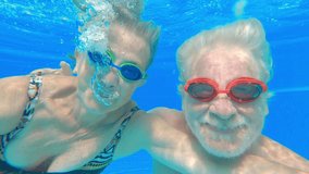 Couple of two happy seniors having fun and enjoying together in the swimming pool smiling and playing. Happy people enjoying summer outdoor underwater waving - Powered by Shutterstock - Get 15% off with code: PIKWIZARD15