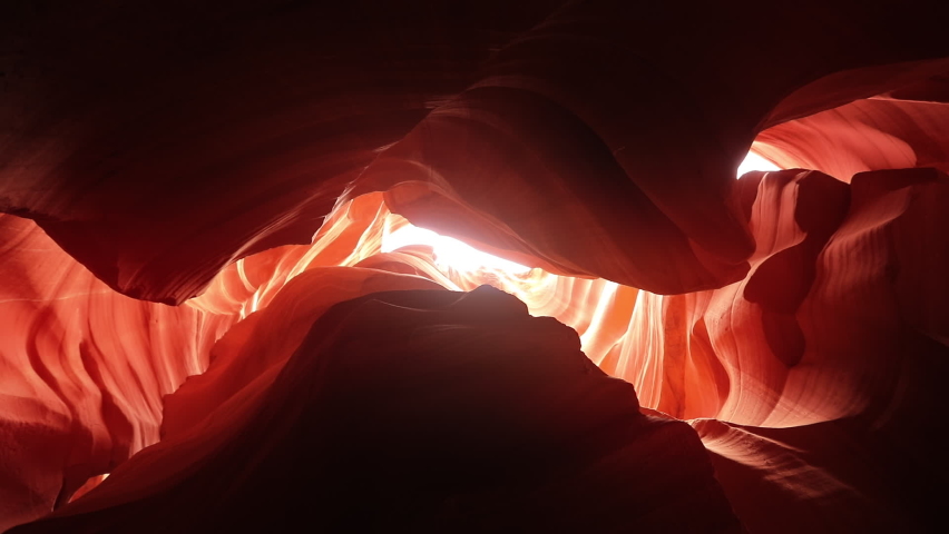 Antelope canyon with smooth and wavy sandstone walls in orange red colors, with sunlight glow reflecting from wave shape canyon. Graceful curves of stunning nature park, Arizona USA travel background Royalty-Free Stock Footage #1080243611