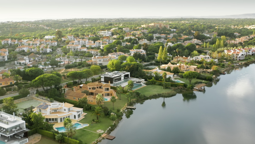 Overview of Quinta do Lago with luxury resorts in Almancil, Algarve, Portugal, Europe. Aerial shot of residential cottages located on banks of lake. Summer landscape on sunny day , 4k footage