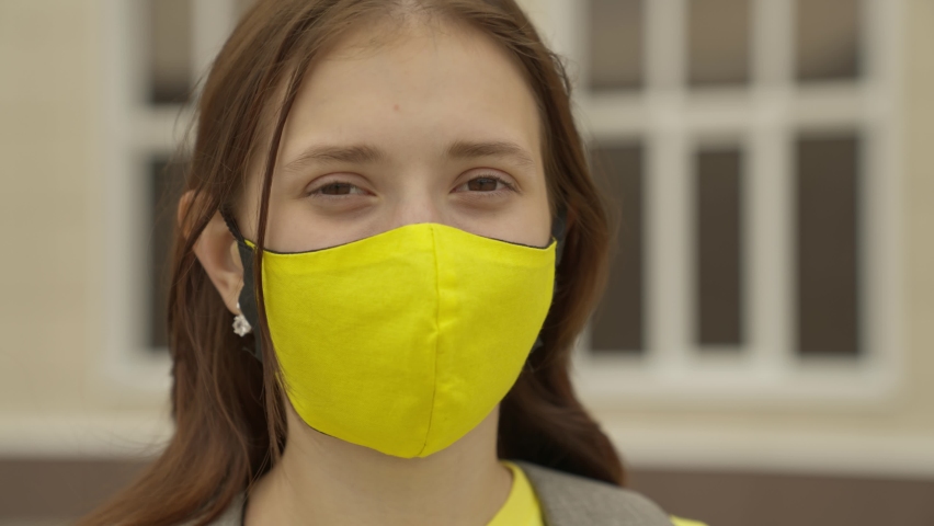 An adult schoolgirl puts on a face mask and smiles, pandemic 2022, filter air for the respiratory tract of the lungs, prevent COVID-19 infection, protect a person from coronavirus with a mask mode Royalty-Free Stock Footage #1080245222