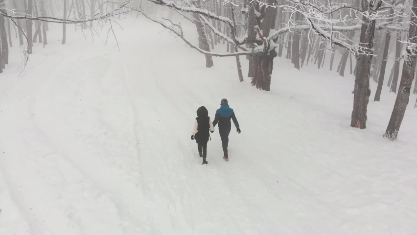 Tracking back view couple hold hand walking together in winter forest surrounded by snowy mystical tranquil landscape. Wonderful Sabaduri forest in Georgia