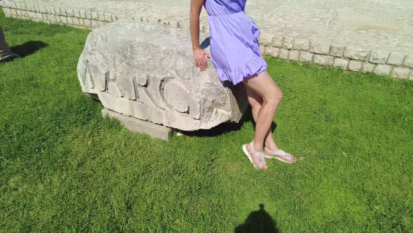 Elegant lady with hat in the Ancient Roman square of Zadar of Croatia, capital of Dalmatia. Old Roman Forum with Cathedral of St. Anastasia and Church of St Donatus with the bell tower.