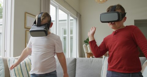 Caucasian boy with brother using vr headsets and standing in living room. family spending time at home.