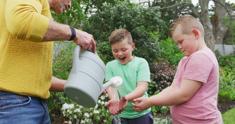 Happy caucasian father with two sons gardening together and washing hands in garden. family spending time at home.