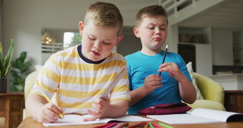 Caucasian boy with his brother sitting at table and learning at home. family spending time at home.