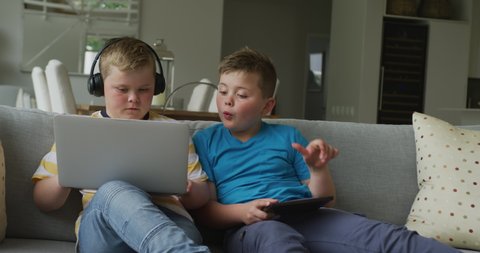 Caucasian boy with his brother sitting in living room and using laptop. family spending time at home.