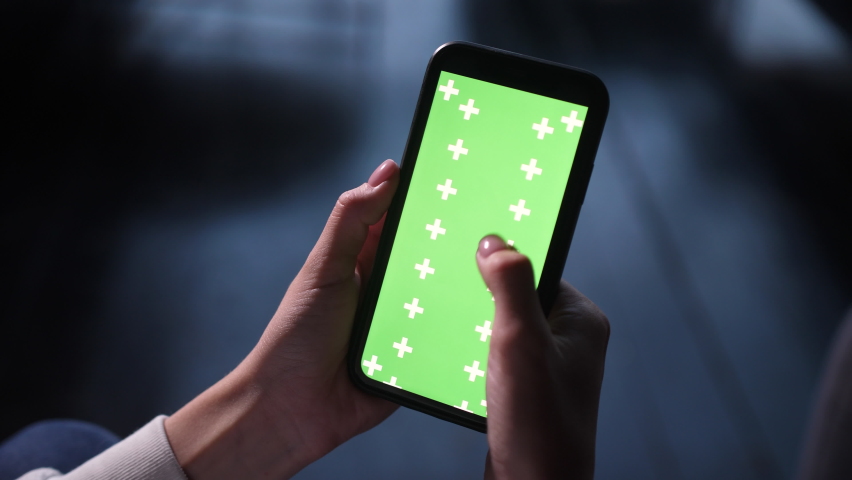 Close up filming of green screen for ads on iPhone. Female holds in hand smartphone device with moving green motion tracking points. Tapping mobile phone screen surface with fingers, swipes left right
