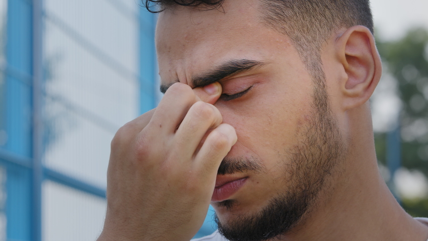 Closeup portrait of tired upset sad young Middle Eastern Arab man rubbing bridge of nose. Millennial Indian guy student touches face, wants to sleep, feels tension, headache, eye fatigue, needs rest Royalty-Free Stock Footage #1080279692