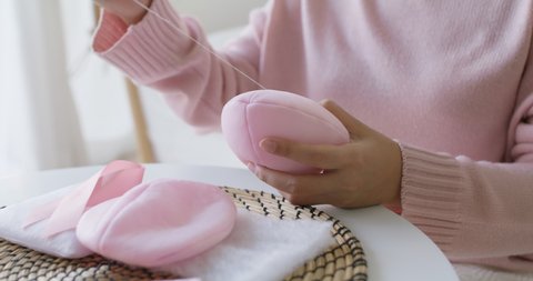 Close-up hand asia woman help make craft pink single fill up bra cup insert for post mastectomy prosthesis surgery MRM at home. Relief work service support give hope to tumor patient medical issue.