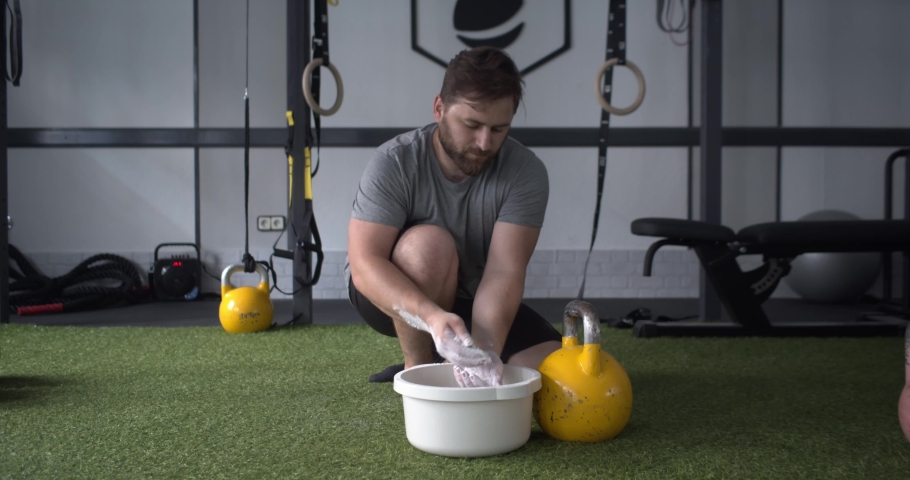 Man getting ready by smearing his hands in magnesium to lift a kettlebell