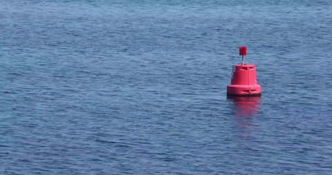 Red buoy floating in the calm blue waters of Lake Grevelingenmeer with light swell, sunny day in Zonnemaire, Zeeland, Netherlands