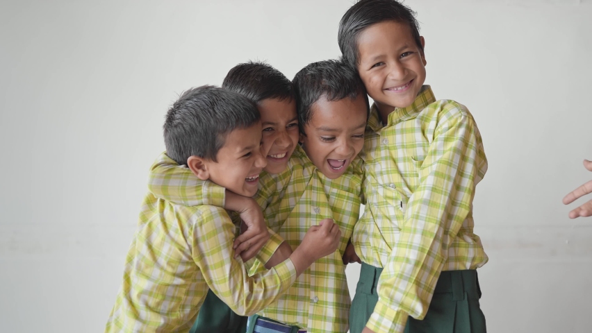 shot of a group of enthusiastic primary school children wearing uniforms with arms holding each other's shoulders looking happy against a white background or wall. learning and education concept Royalty-Free Stock Footage #1080285341