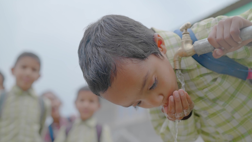 Close up shot of a young little school boy with a backpack drinking clean water from a running tap in a rural village and his waiting for their in the back. Concept of a natural resources conservation | Shutterstock HD Video #1080285479