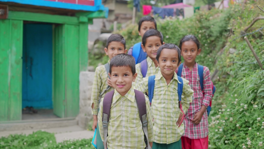 Shot of a group of happy and adorable primary Indian Asian school children kids wearing uniforms with backpacks walking through a rural village lane. school re opening, learning, and education concept Royalty-Free Stock Footage #1080285710