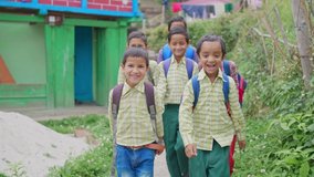 Shot of a group of happy and adorable primary Indian Asian school children kids wearing uniforms with backpacks walking through a rural village lane. school re opening, learning, and education concept - Powered by Shutterstock - Get 15% off with code: PIKWIZARD15