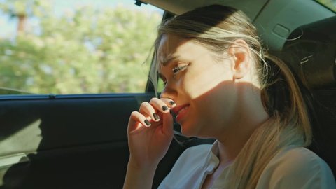 Sad crying young woman traveling in backseat of car. Unhappy, problematic young woman can't stand what she's going through and cries. Portrait of unhappy young woman.