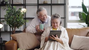 Asian mature senior couple using tablet and spending time together in living room at home. - Powered by Shutterstock - Get 15% off with code: PIKWIZARD15