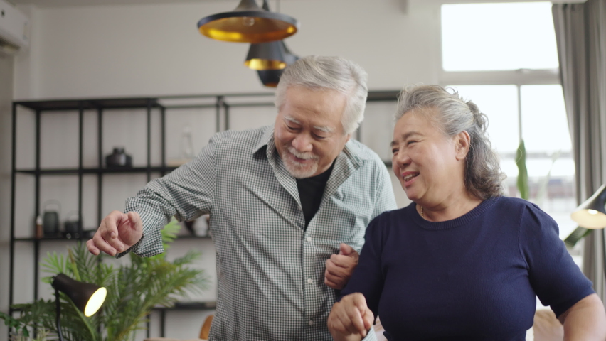 Slow motion Asian mature senior couple is dancing and smiling at home. Royalty-Free Stock Footage #1080302984