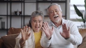 Asian mature senior couple look talk to camera and waving hand at home. video calling communicate in online chat