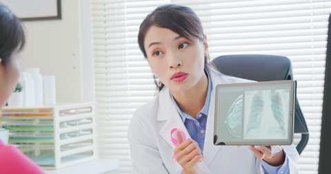 close up of asian woman has breast cancer diagnosis in hospital - female doctor showing mammography test results and xray to patient on digital tablet