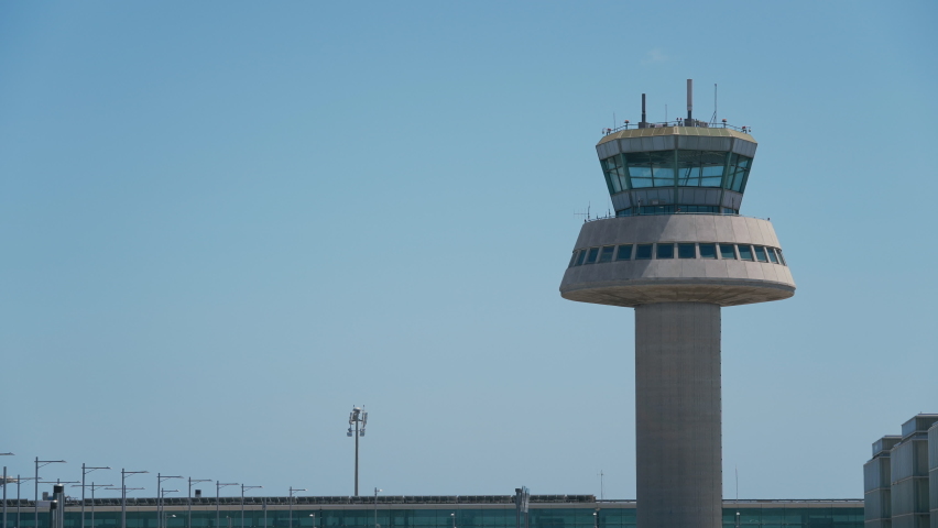 Blue airplane taking off next to an air traffic control tower