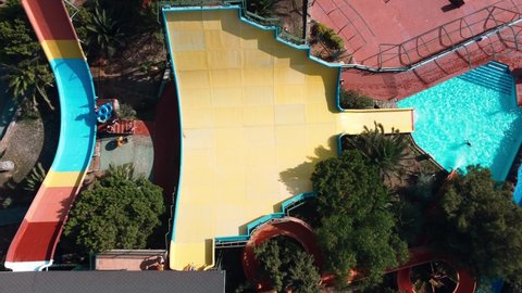 Aerial view of a man riding an inflatable ring on a slide in a water park.