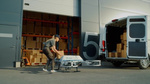 Storage Facility Female Employee Loads Up Autonomous Flying Delivery Drone with a Parcel, Confirms Destination. Futuristic Parcel Drone Takes Off on Flight from Warehouse to Client Waiting for Package